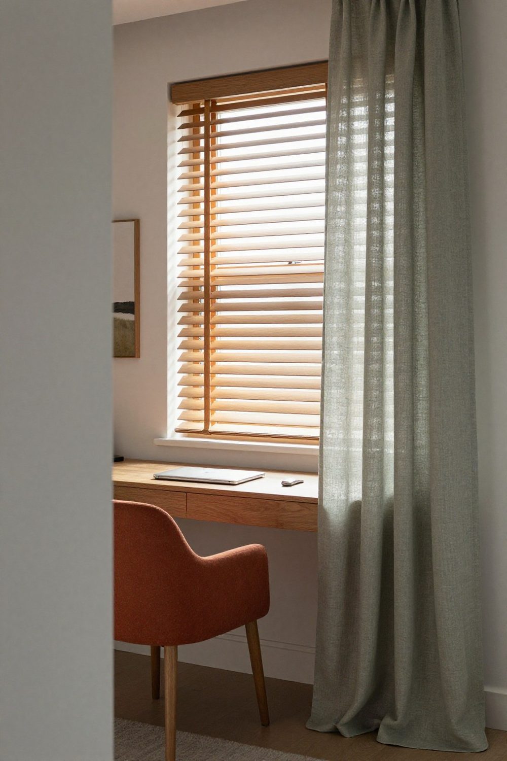 Home office with linen curtains and wooden blinds controlling the daylight on the desk